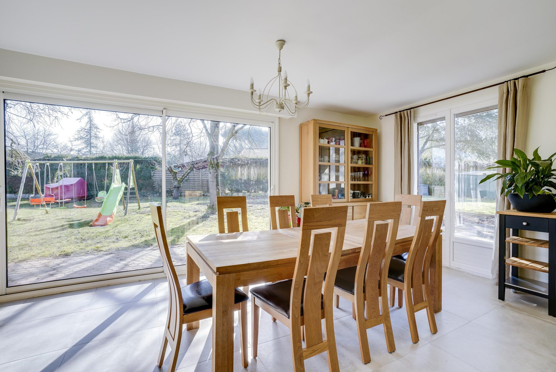 Salle à manger de maison rénovée avec table en bois et baie vitrée sur jardin