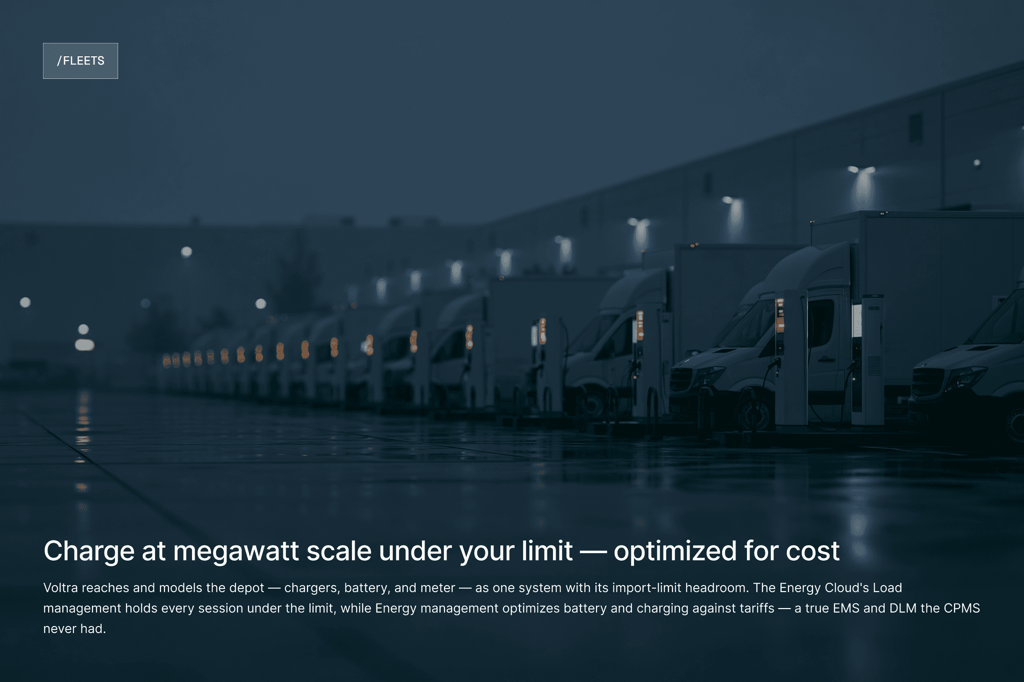 Row of electric semi-trucks parked at a depot at night.
