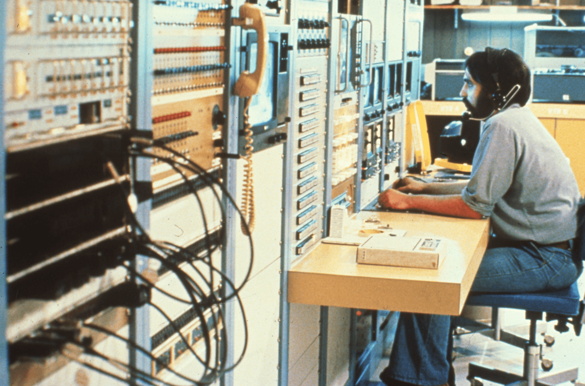Vintage photo of a technician wearing a headset at a telephone switching equipment console