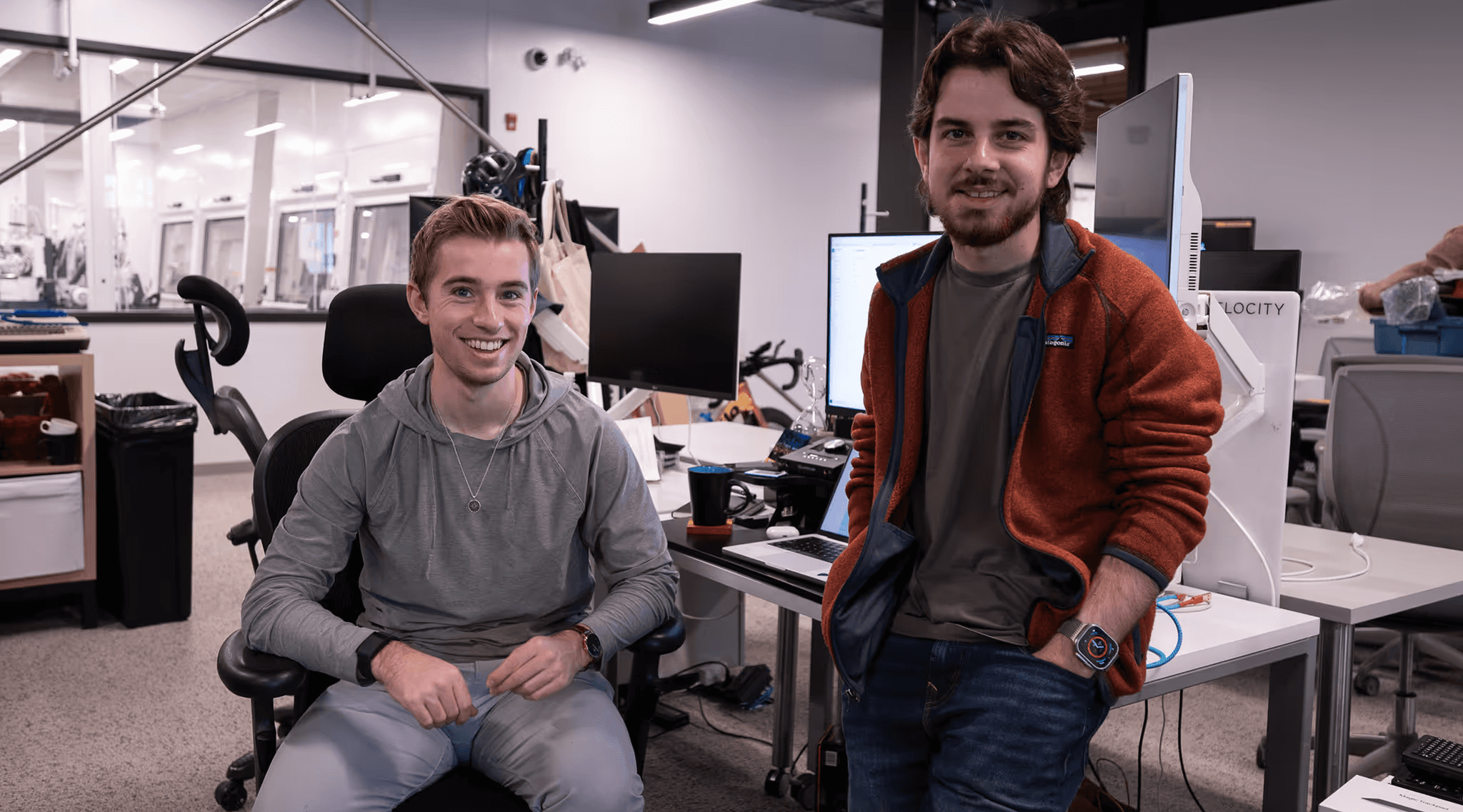 Voltra's two founders in the office, one seated at a desk and one standing beside him