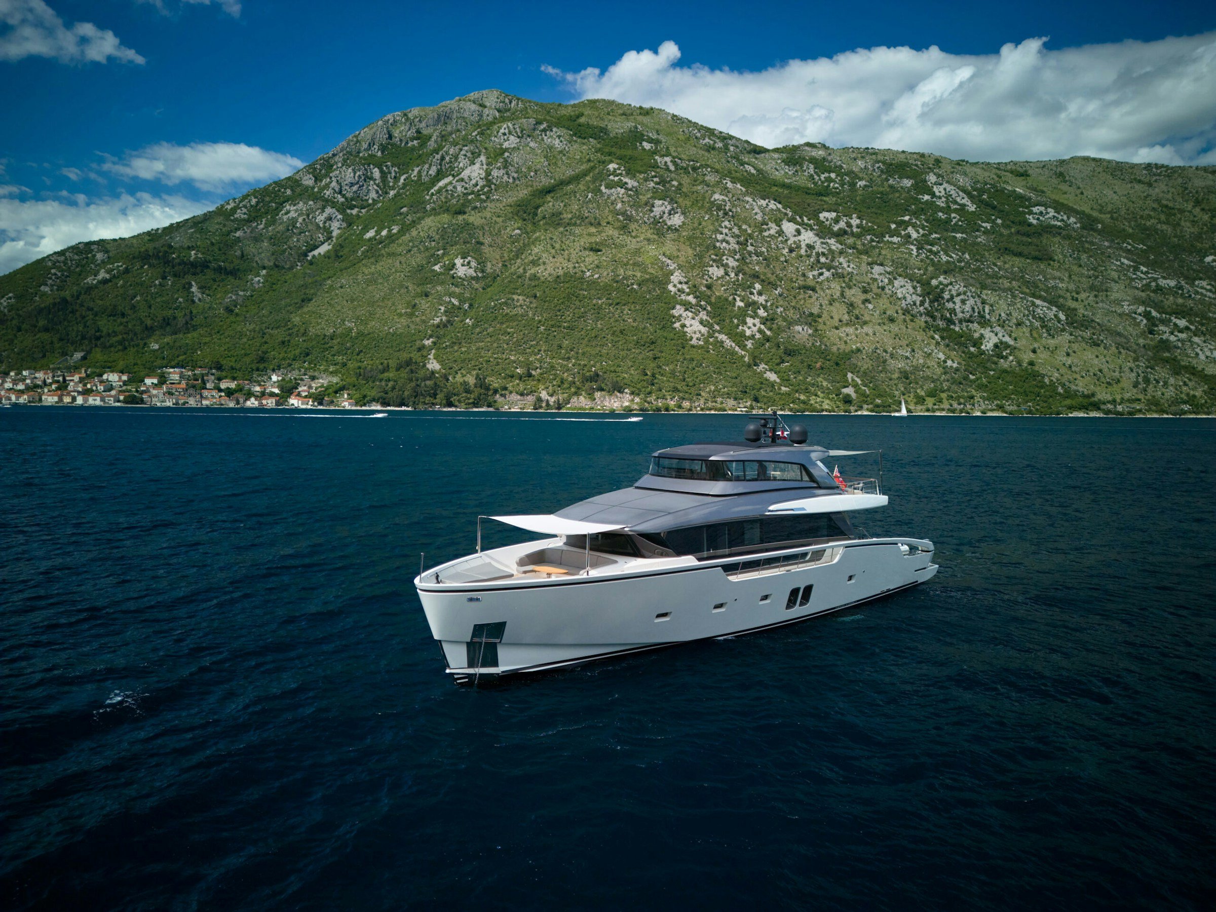 Aerial view of Zaffiro III, the 26.52m Sanlorenzo SX88, on a deep blue bay below green mountains