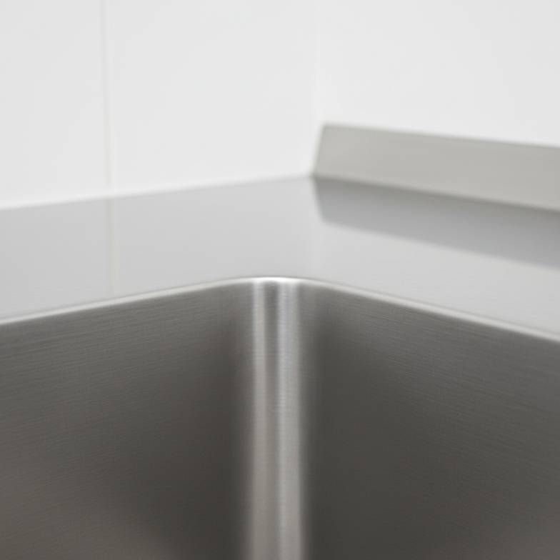 Close-up of a seamless, coved corner inside a stainless steel sink, showing it is easy to clean.