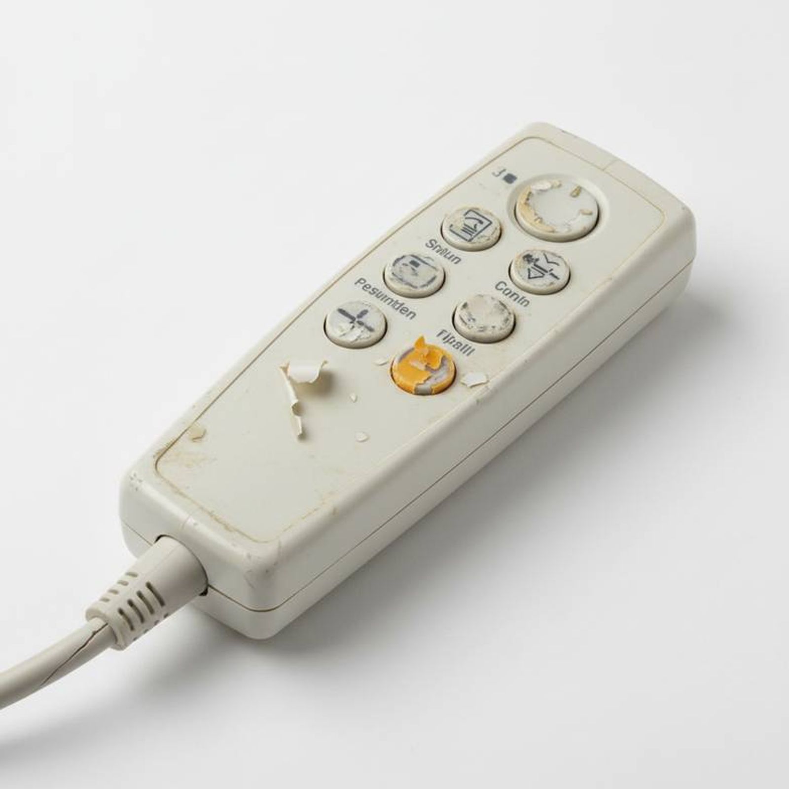 A worn-out hospital bed hand control with peeled labels and a frayed cable.