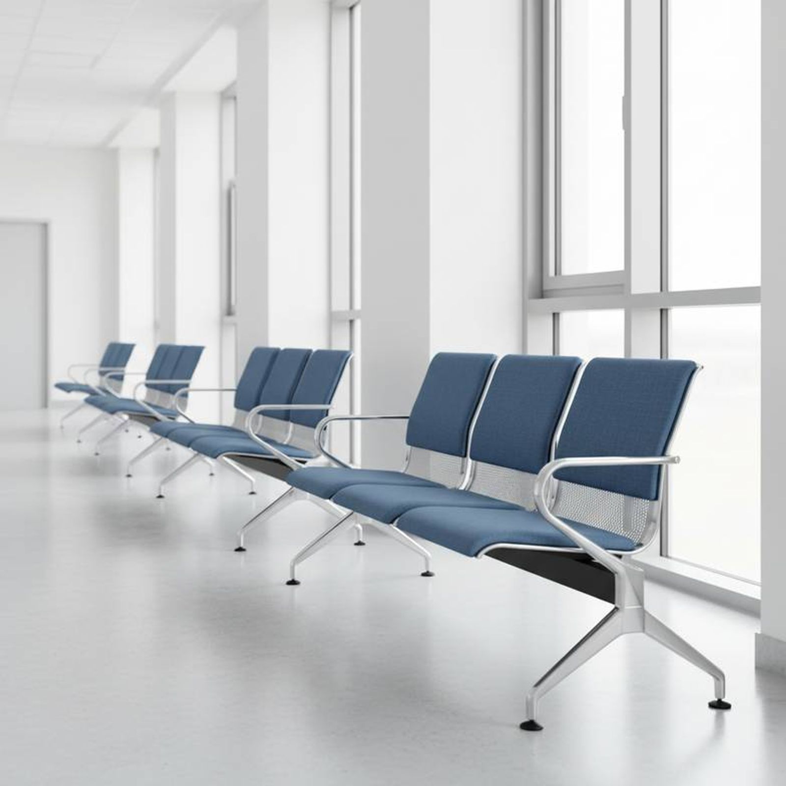 A row of modern hospital waiting chairs in a clean, bright hospital corridor.