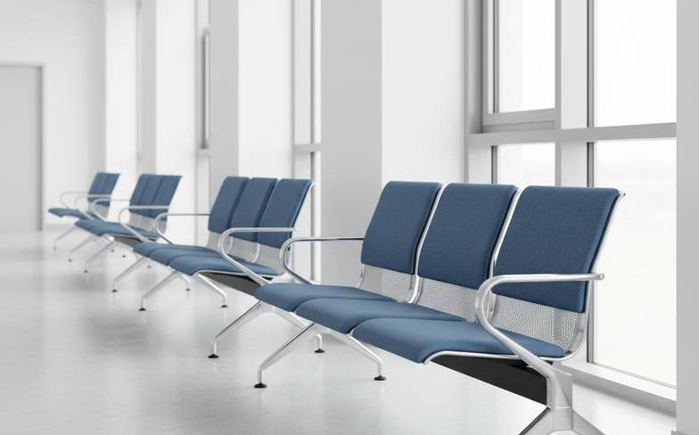 A row of modern hospital waiting chairs in a clean, bright hospital corridor.