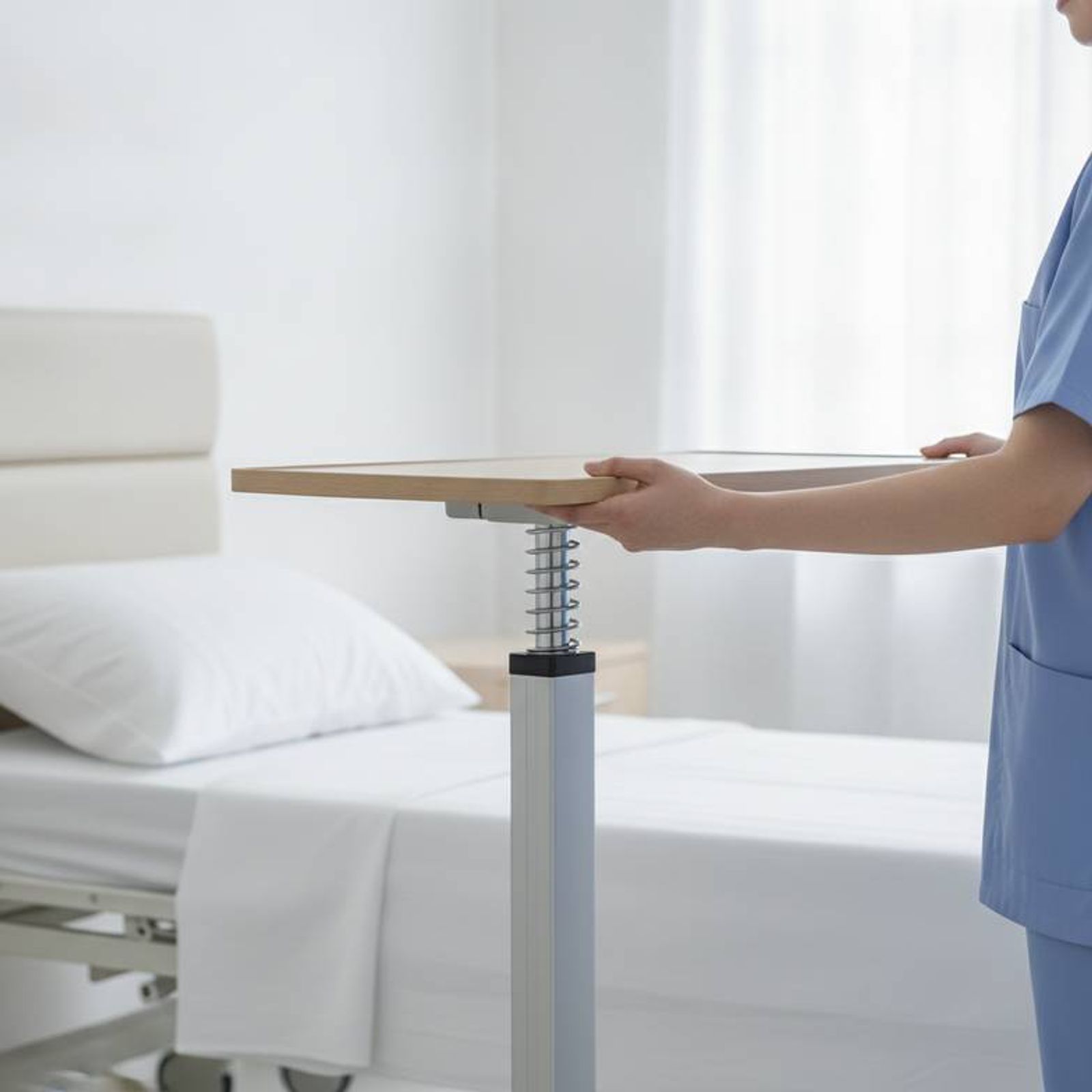 A nurse easily adjusting an overbed table next to a hospital bed in a patient room furniture package.