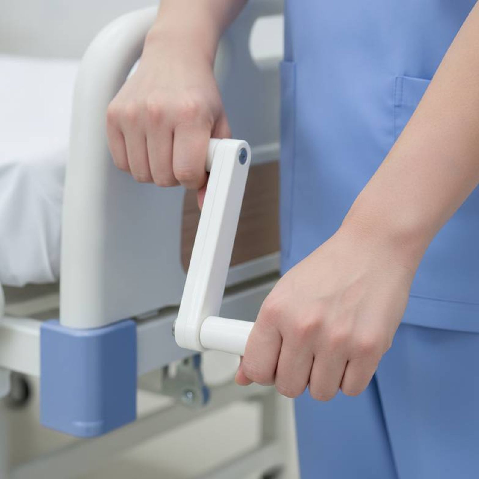 A nurse easily adjusting a manual hospital bed using a smooth hand crank.