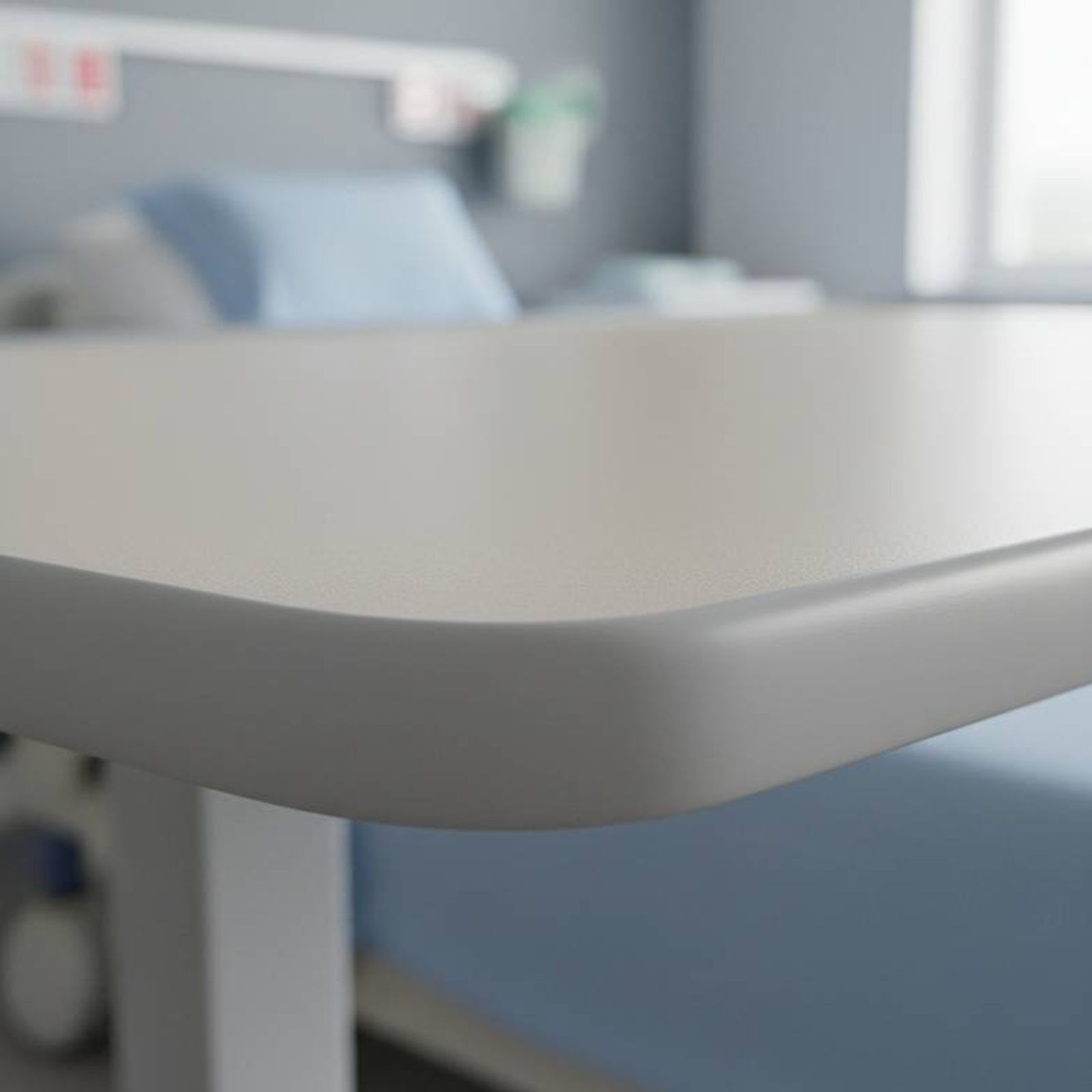 A close-up shot of an overbed tabletop, highlighting the durable, seamless molded edge and the easy-to-clean surface texture.