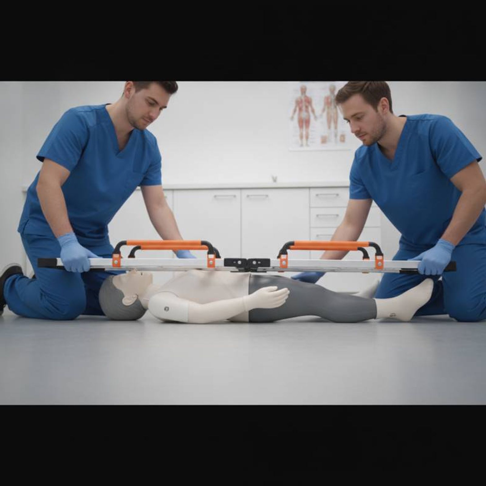 Medical staff demonstrating how a scoop stretcher separates into two halves to slide under a patient on the floor.