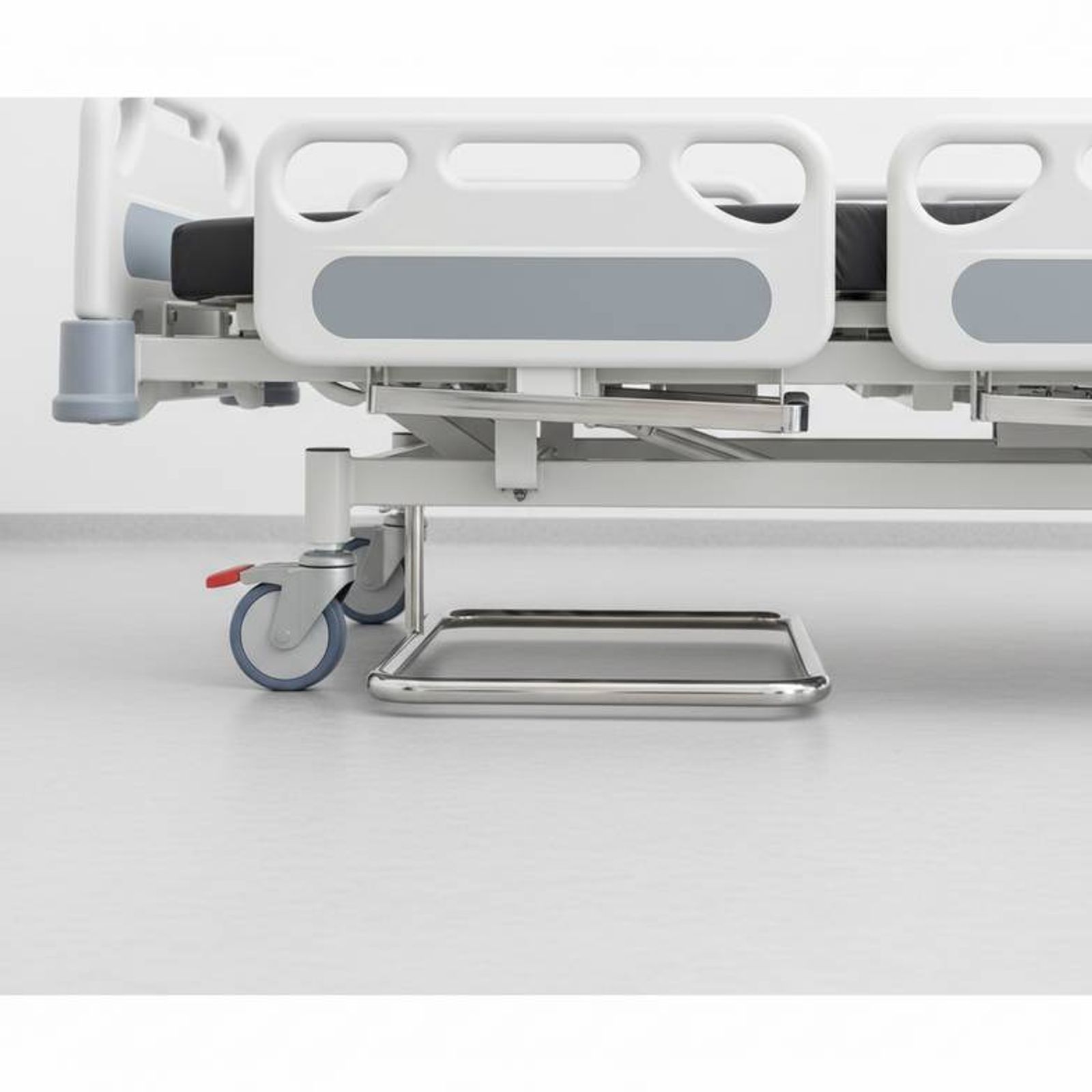 A close-up view showing the hospital bed under-bed clearance and the legs of an overbed table.