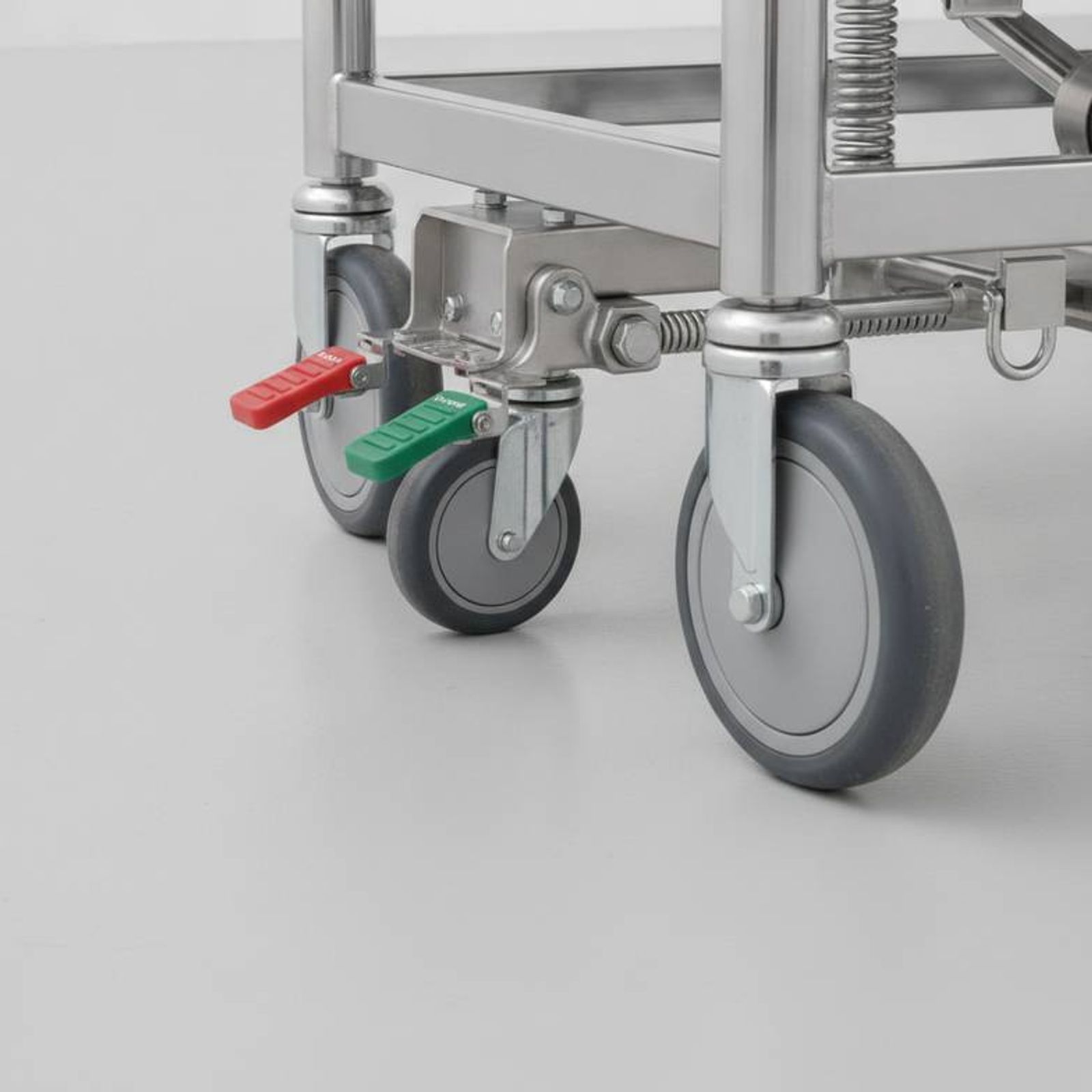Close-up of the central braking pedal and a fifth wheel on a patient transfer trolley