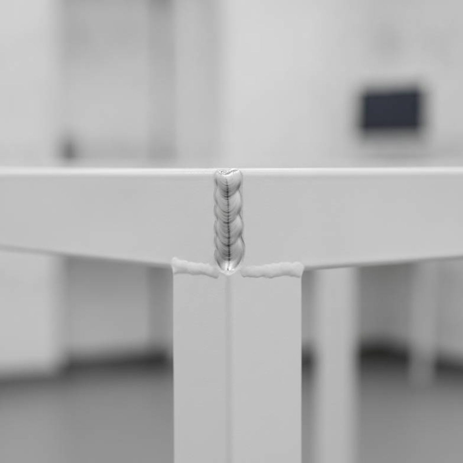Close-up view of a robot-welded steel frame on a medical exam table, highlighting structural integrity