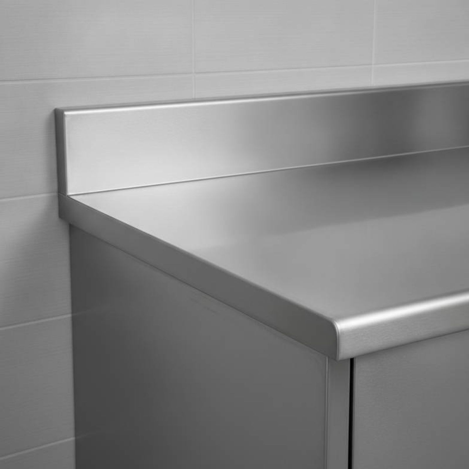 A close-up photo of a stainless steel medical counter showing an integrated backsplash and a raised marine edge.