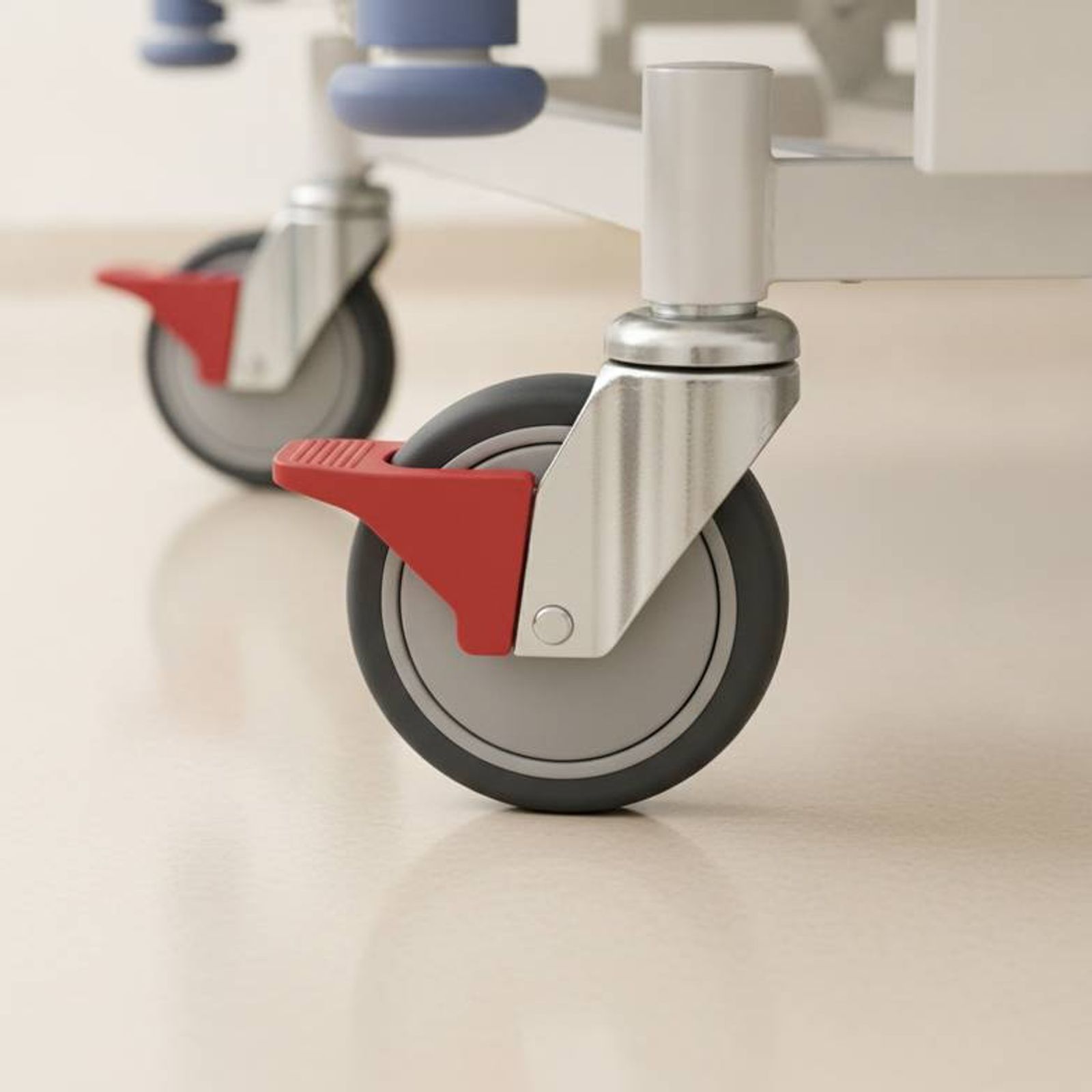 Close-up of the central braking pedal and a large, heavy-duty caster on a bariatric hospital bed.