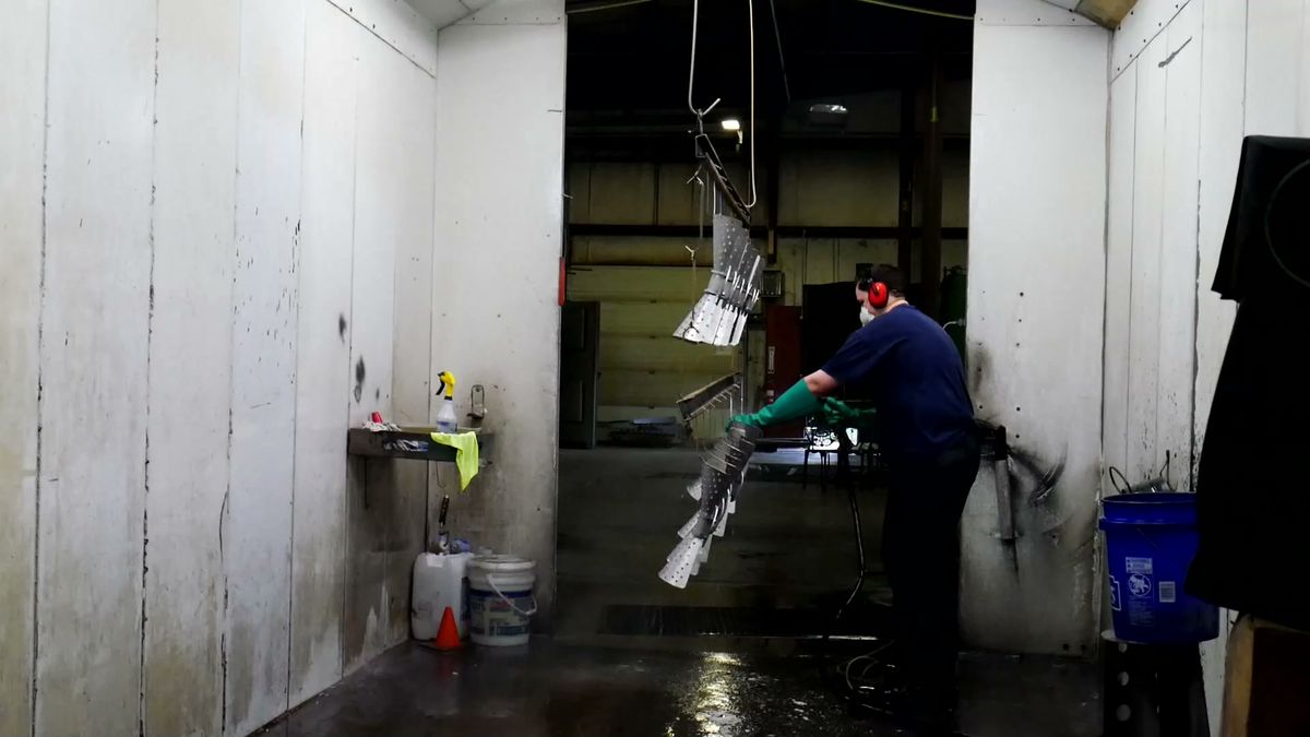 Technician applying powder coat finish to chandelier components