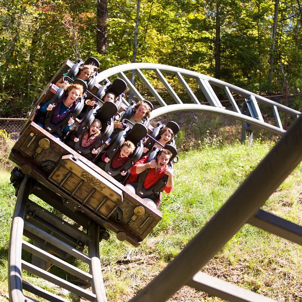 Riders scream with excitement as the Mystery Mine coaster dives through sharp twists surrounded by trees at Dollywood. The mine-themed ride combines thrilling drops with the beauty of the Smoky Mountains.