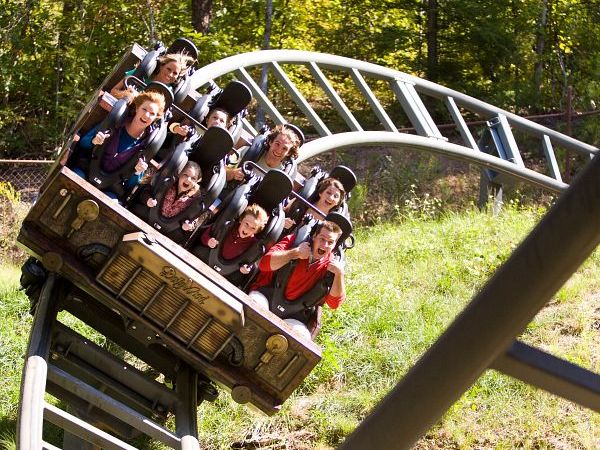 Riders scream with excitement as the Mystery Mine coaster dives through sharp twists surrounded by trees at Dollywood. The mine-themed ride combines thrilling drops with the beauty of the Smoky Mountains.