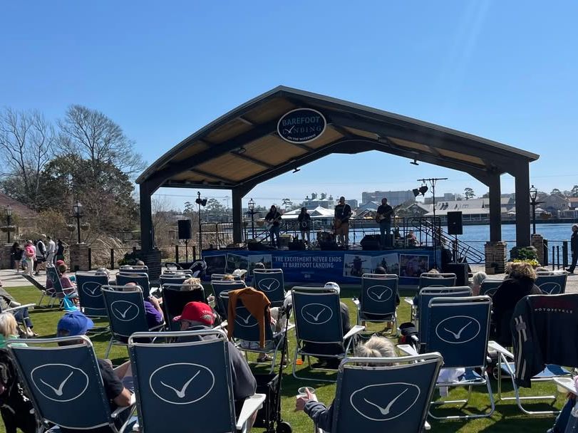 Outdoor live music performance at Barefoot Landing in North Myrtle Beach, with guests relaxing in lawn chairs by the scenic waterfront.