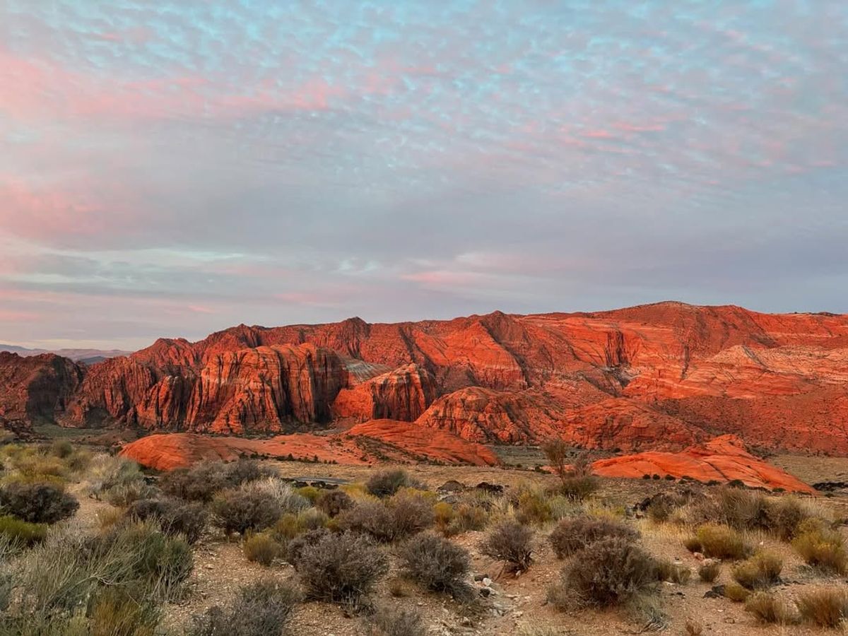 Hikers explore the dramatic red sandstone cliffs of Snow Canyon State Park, a popular destination in southern Utah for outdoor adventures.