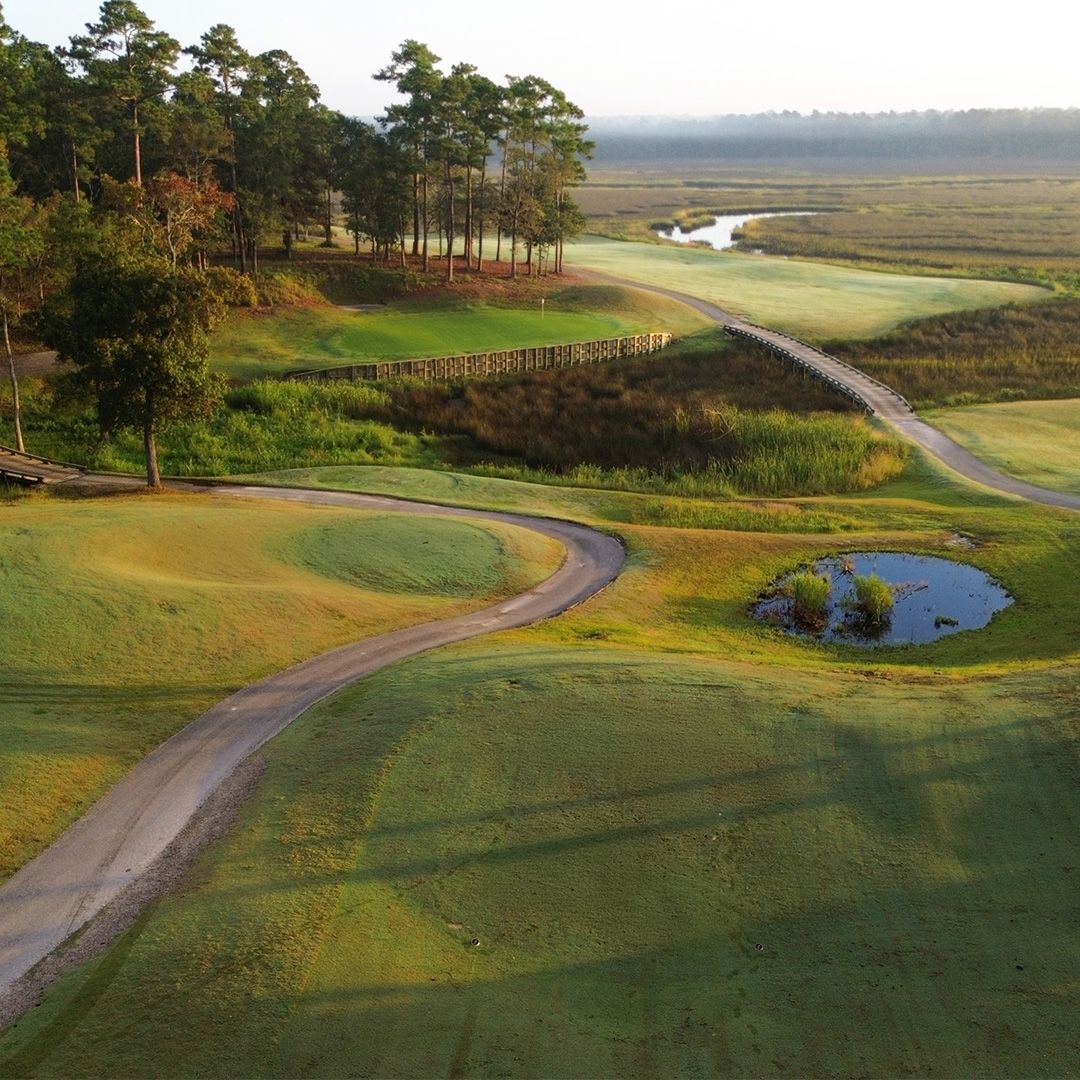 Rivers Edge Golf Club shows a winding path through lush greens with water and marshland surrounding the course. The natural views create a calm and scenic golf experience.