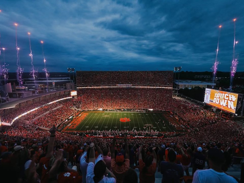 A packed Clemson Tigers football stadium erupts with cheers and fireworks after a touchdown. This thrilling game-day experience is a must for any college sports fan.