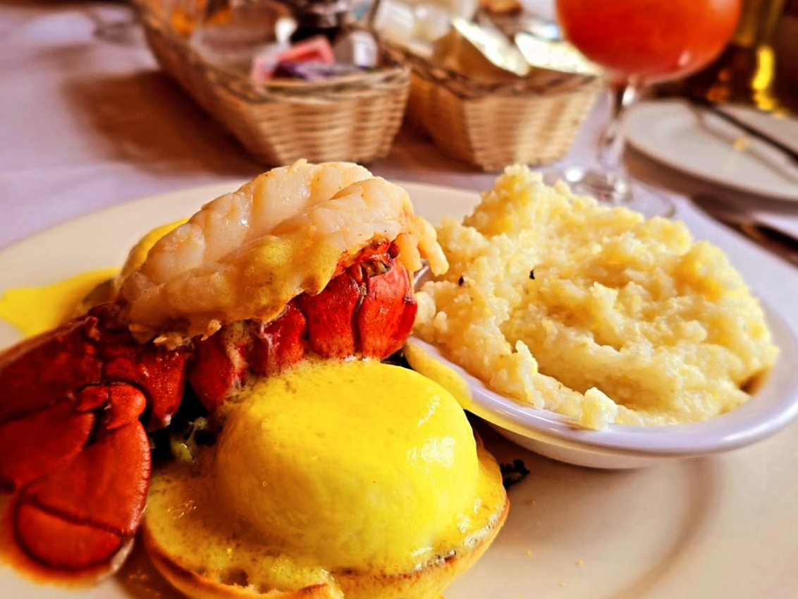 Lobster on table with muffin next to it and butter melted on top next to potatoes