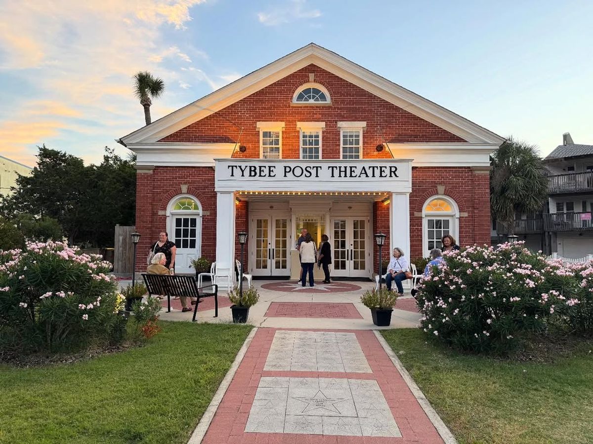 The Tybee Post Theater glows warmly as guests gather outside its historic red-brick building. Surrounded by blooming flowers, this landmark blends local history with community entertainment.