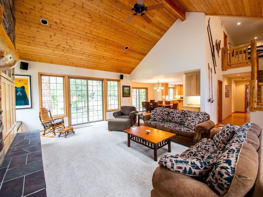 A cozy cabin sits among tall pine trees in Sunriver, Oregon, with a view of snow-capped mountains in the distance. This peaceful setting captures the natural beauty and outdoor charm of Sunriver, perfect for a relaxing getaway.