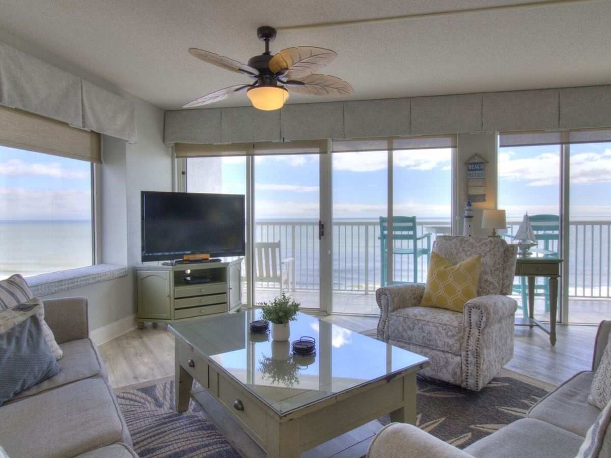 Comfortable living room with beachy decor, soft seating, and a private balcony with endless ocean views. It’s the kind of space where you’ll want to stay in your pajamas a little longer.