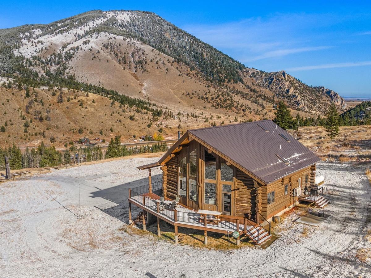 Wooden cabin with snow melted surrounding it and mountaintop