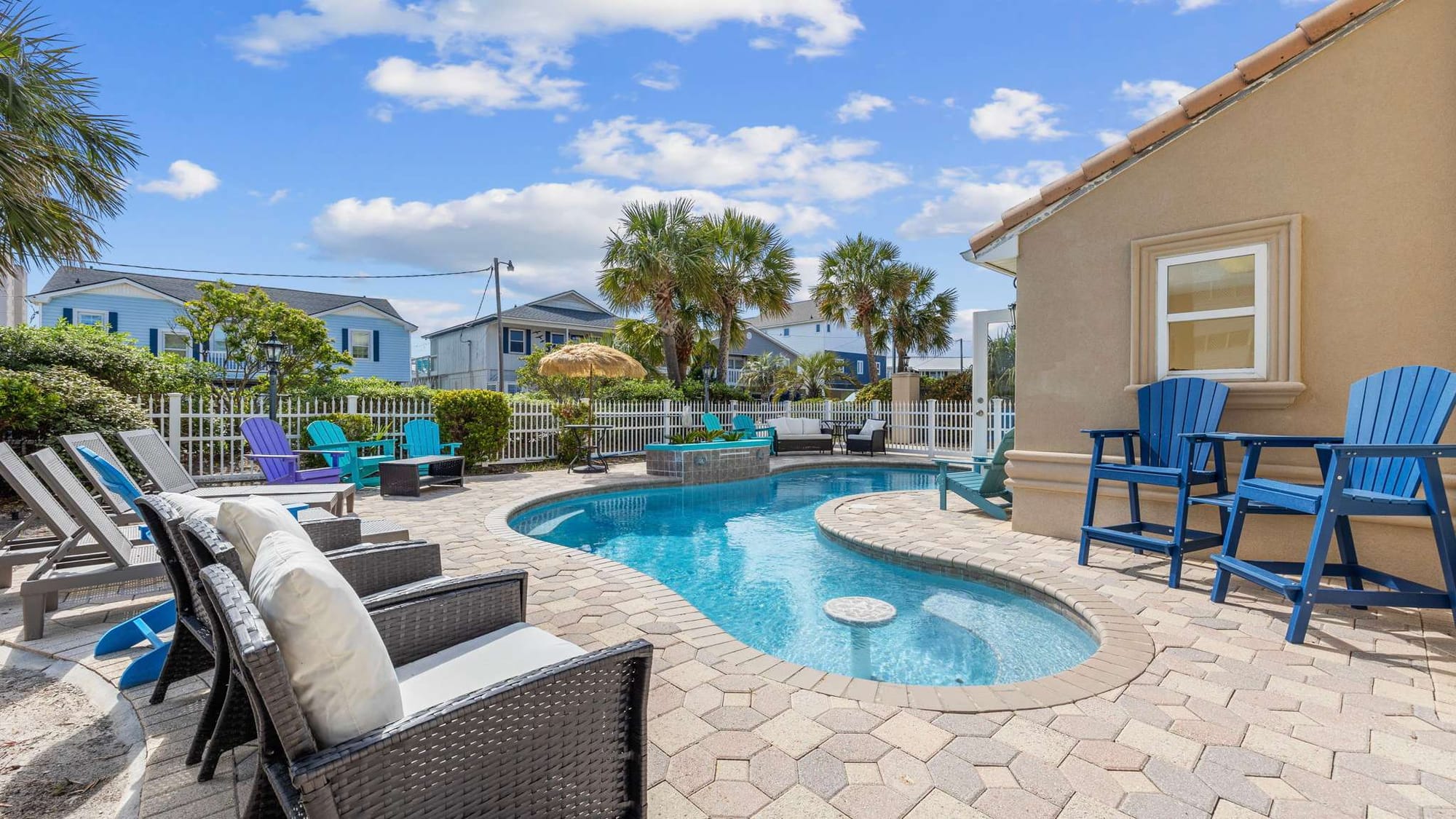 Palm trees frame this tropical backyard complete with a pool, hot tub, and bright red umbrellas. It’s a dreamy North Myrtle Beach escape where big families gather to relax, grill, and enjoy golden sunsets.