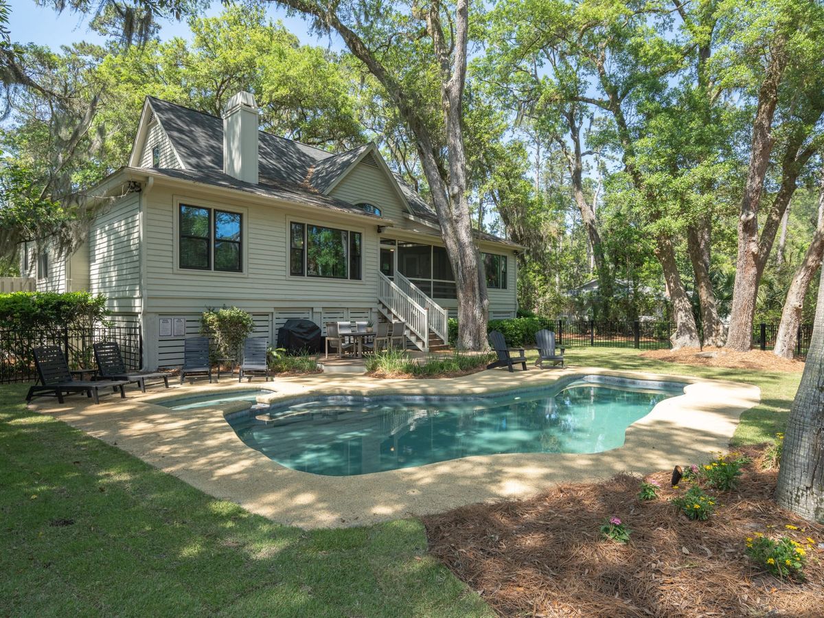Charming low-country home surrounded by trees, featuring a private pool, cozy loungers, and a peaceful backyard—ideal for quiet family getaways. Enjoy the blend of nature and comfort with this spacious retreat.