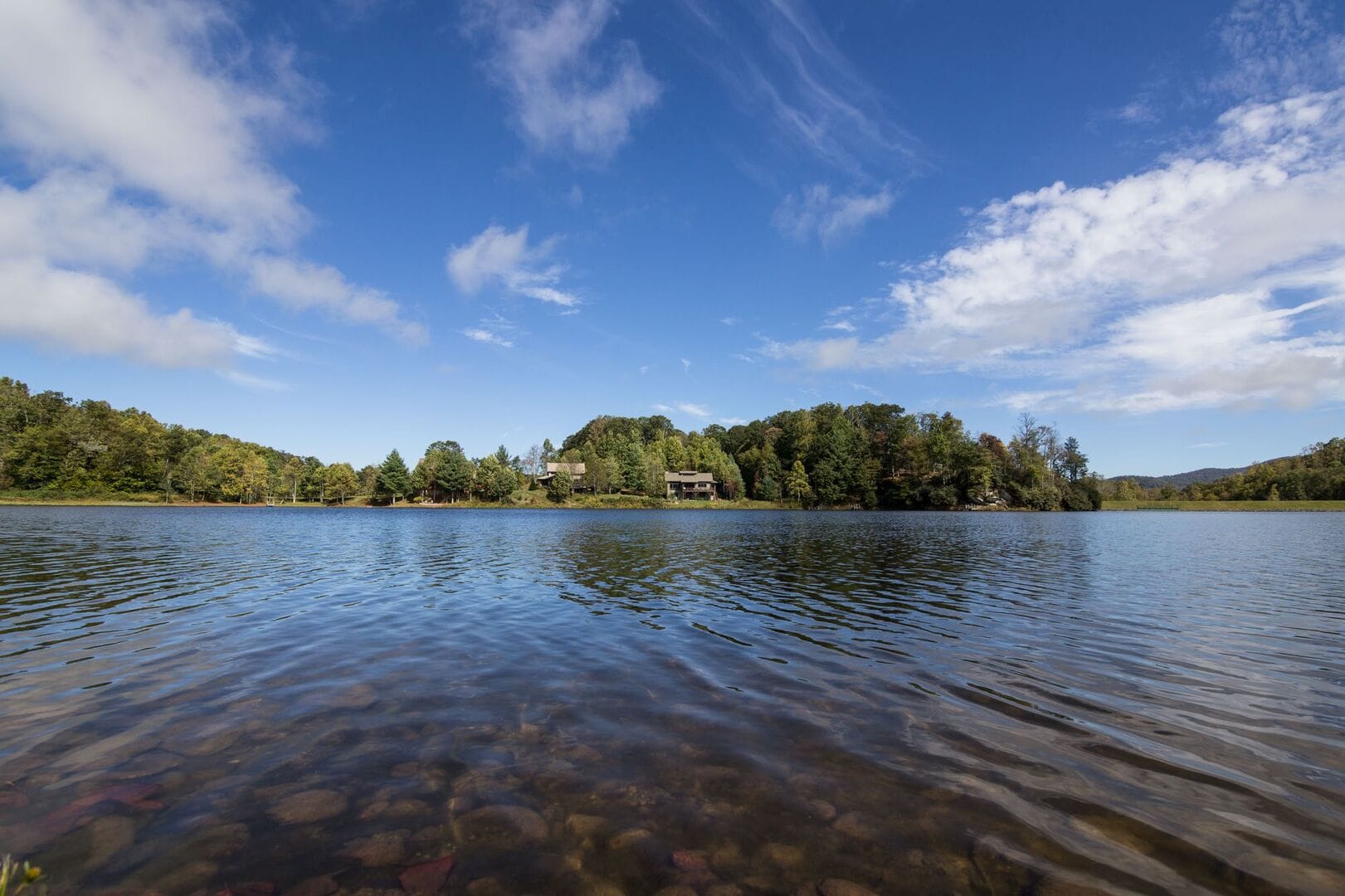 A wooden dock stretches out over a calm mountain lake, surrounded by trees turning shades of green and orange. It’s the kind of place campers love—simple, quiet, and close to nature.