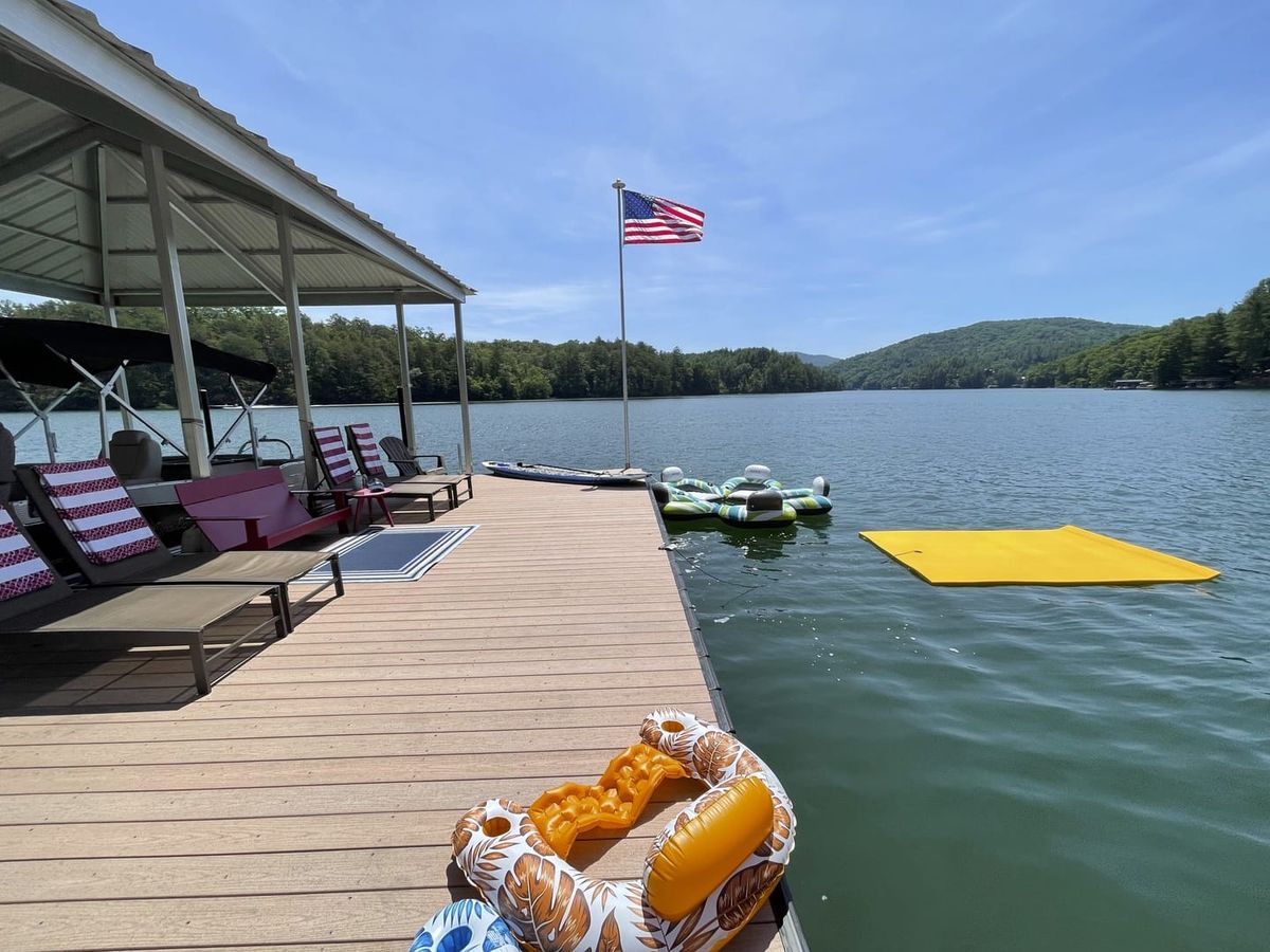 A sunny dock on a calm lake is lined with loungers, a boat, and colorful floats. It’s a guest-ready setup that makes outdoor fun and relaxation effortless.