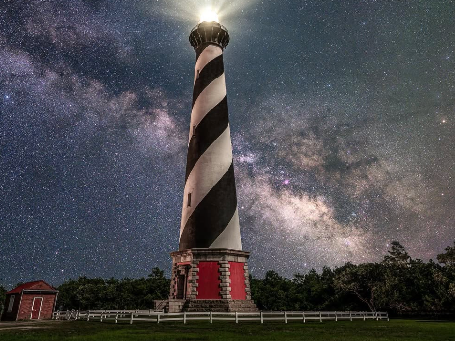 black and white striped lighthouse with stars in the sky