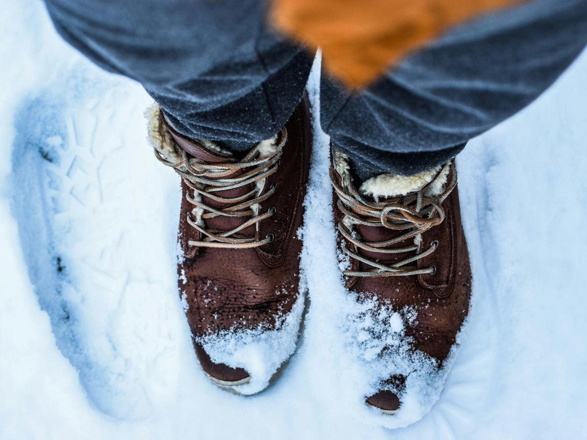 Person with wwo brown boots standing on snow