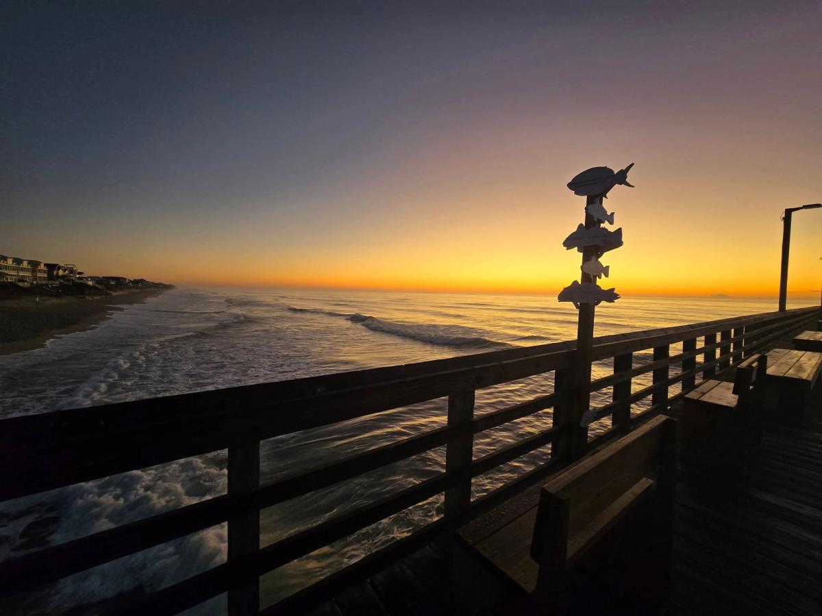 The Surf City Ocean Pier stretches over the waves at sunrise, casting golden light on the beach. This early morning view is a must-see for pier fishing and peaceful walks.