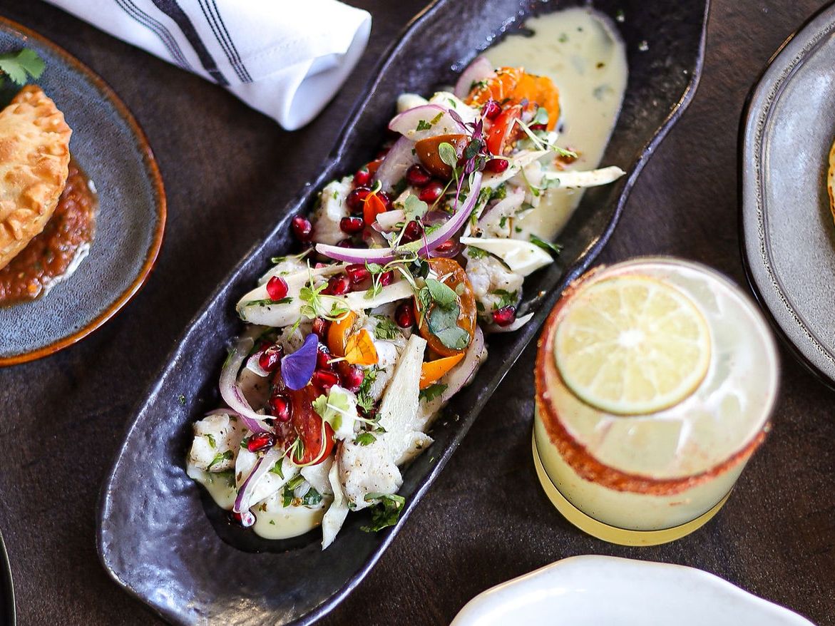 A vibrant Mexican feast at Reyes Mezcaleria featuring empanadas, ceviche with pomegranate seeds, tacos, and a refreshing lime cocktail. Bold flavors meet colorful presentation.