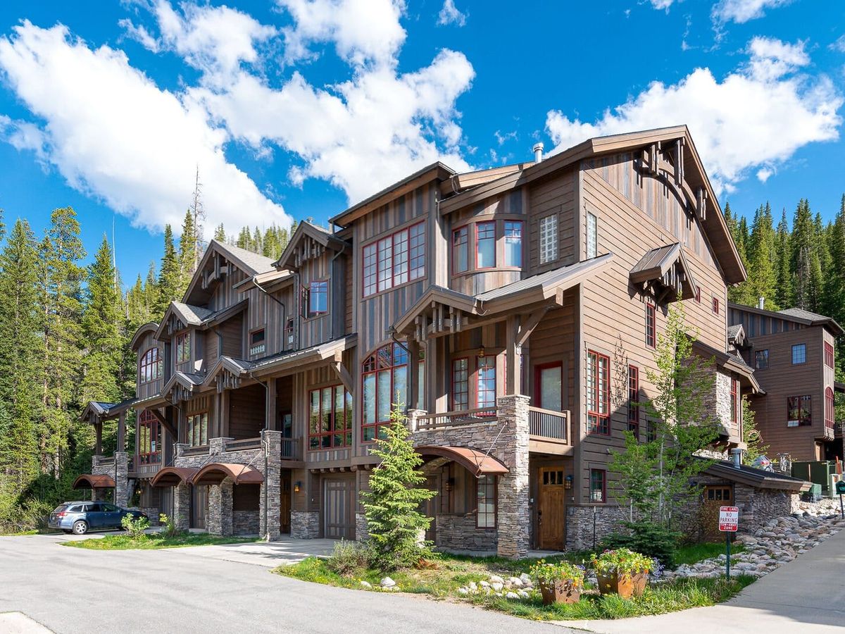 A rustic yet modern mountain townhouse in Winter Park, Colorado, surrounded by tall pines. The blend of natural wood and stone details makes it an inviting retreat year-round.