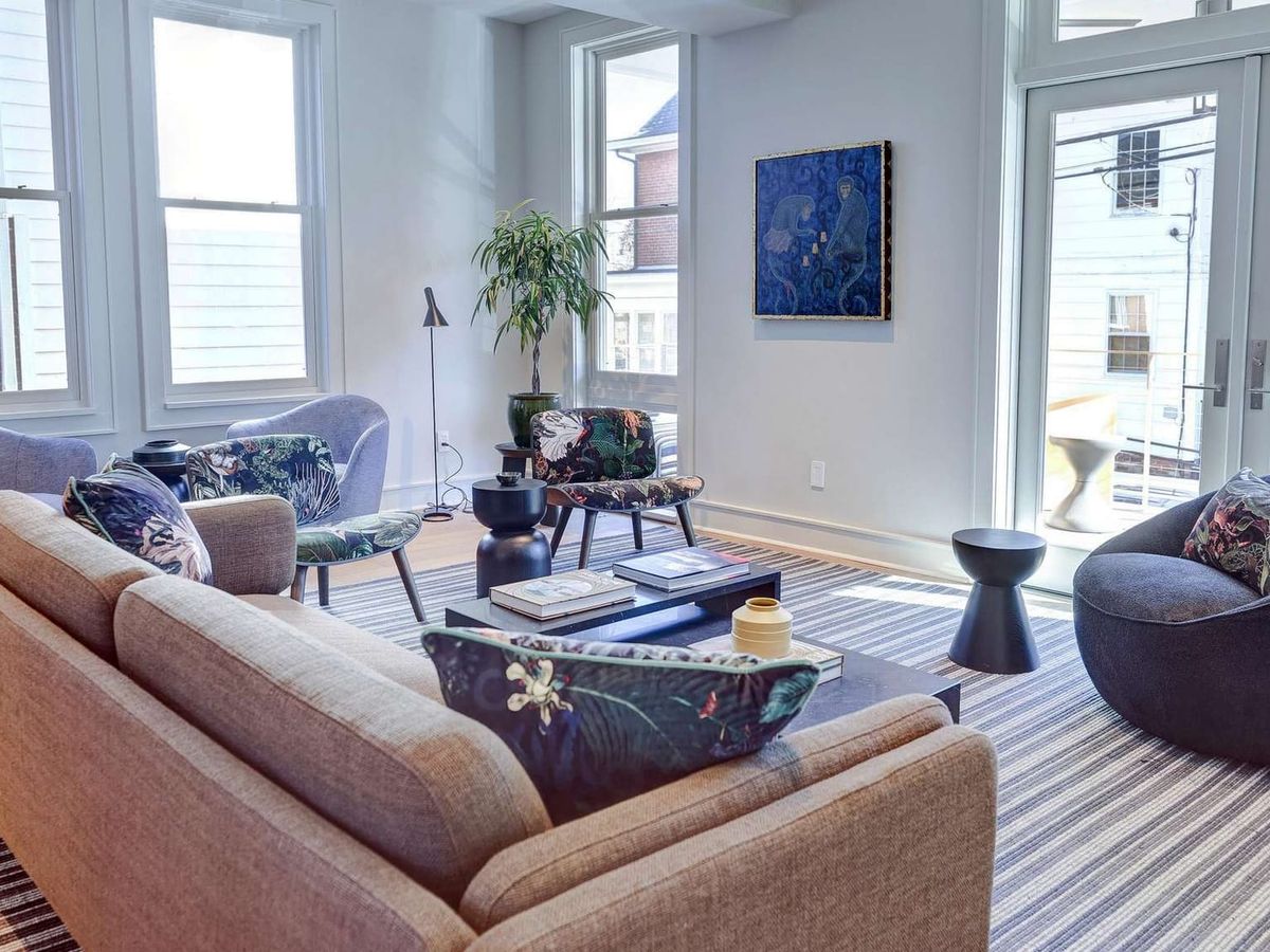 This elegant yellow guest house features classic French-style architecture with blue shutters and tall glass doors. Surrounded by lush greenery, it's a charming escape with plenty of natural light and timeless curb appeal.