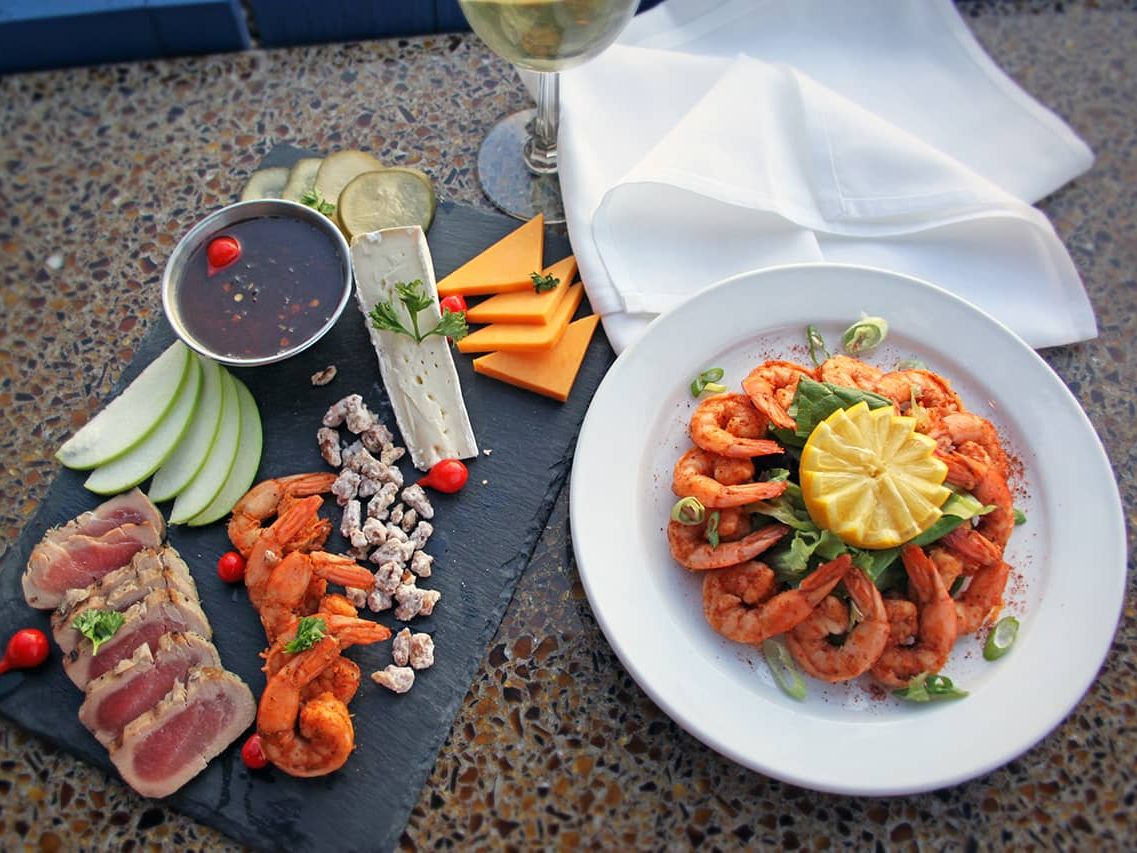 A coastal platter of shrimp, cheese, and seared tuna served with a glass of white wine at South Beach Grill. The elegant seafood presentation reflects the restaurant’s fresh and flavorful approach to waterfront dining.