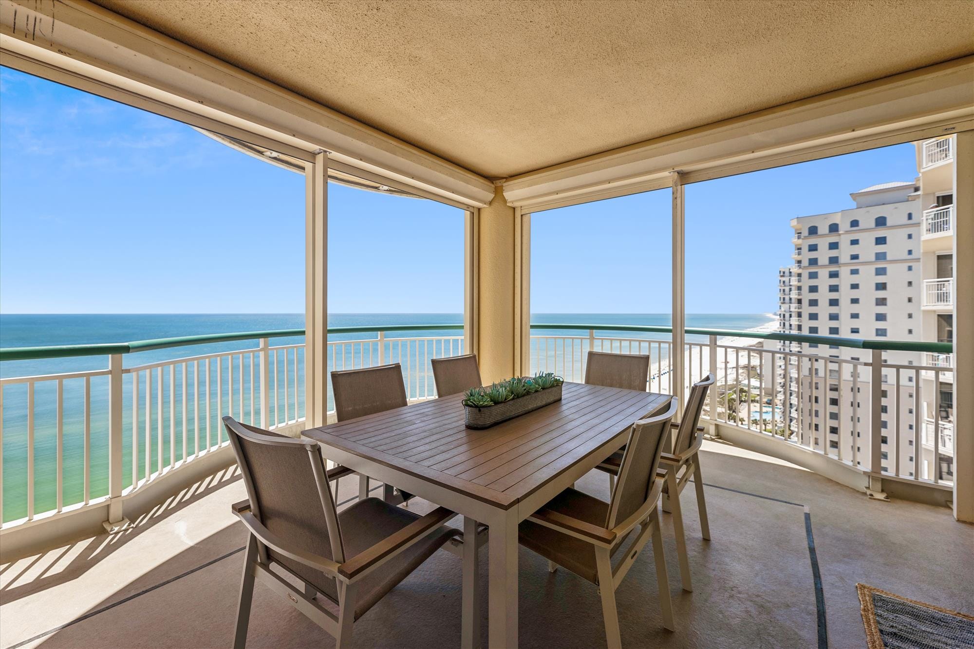 This spacious balcony dining area offers endless views of the emerald Gulf waters, ideal for outdoor meals with ocean breezes. The modern furniture and open design make it easy to relax and enjoy the coastal beauty.