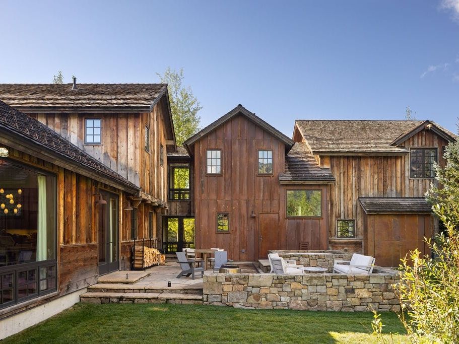 Spacious log cabin with large windows, cozy mountain decor, and a warm fireplace surrounded by plush seating, perfect for family game nights after skiing. Set against a snowy backdrop in Jackson Hole, this luxury stay offers peace, comfort, and plenty of room for the whole crew.