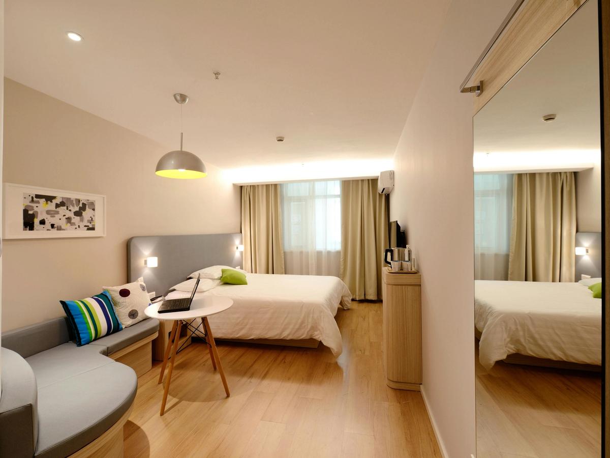 A clean, well-lit hotel room with wood flooring, a large bed, and modern furniture. The space shows how guests can enjoy style and comfort without overspending.