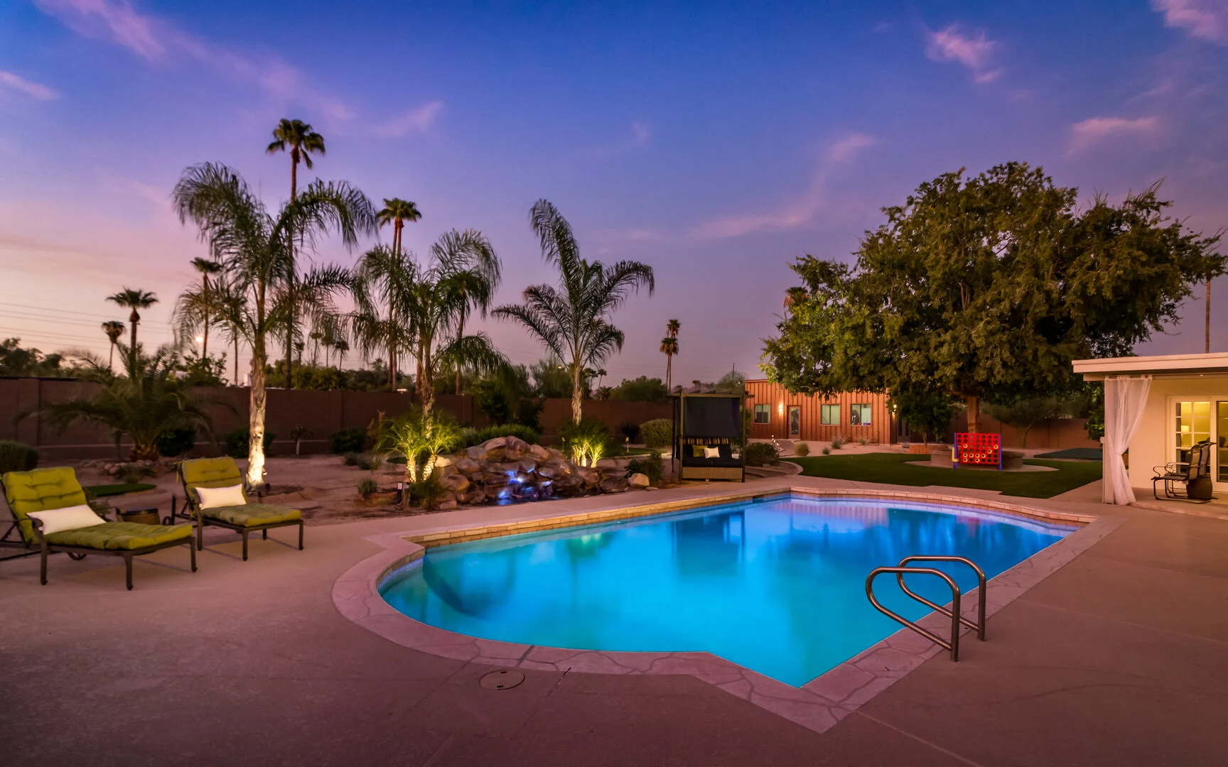 Private pool with green chairs and palm trees in the background