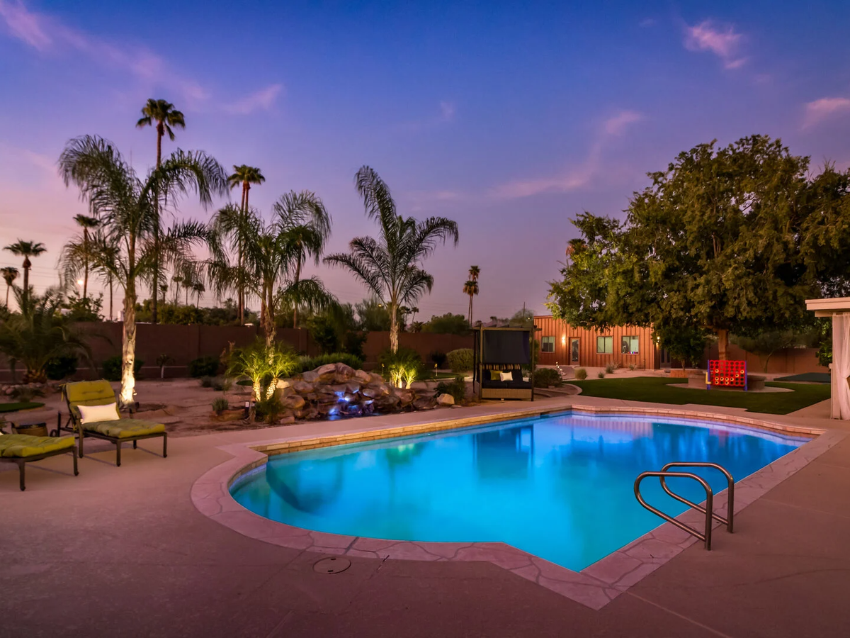 Private pool with green chairs and palm trees in the background