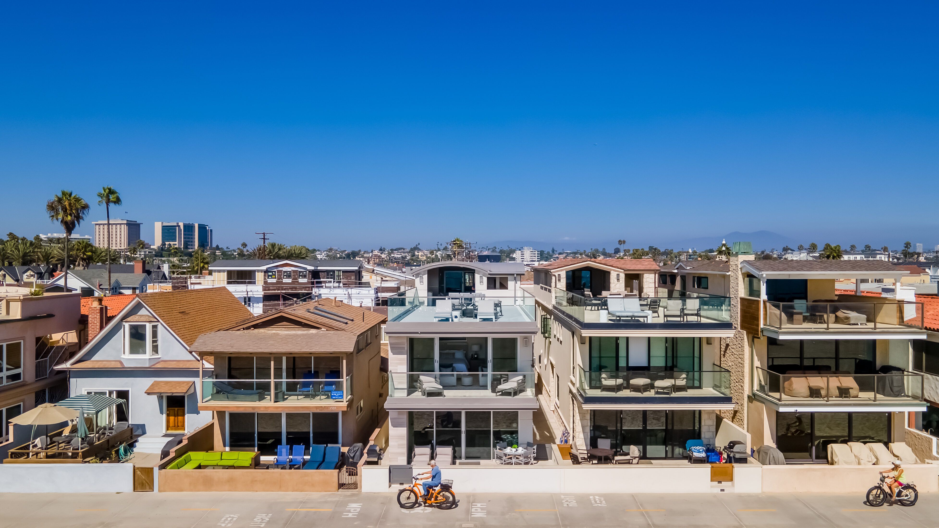 Modern beachfront homes along the Newport Beach boardwalk, featuring luxury vacation rentals with glass balconies, ocean views, and direct beach access in Southern California.