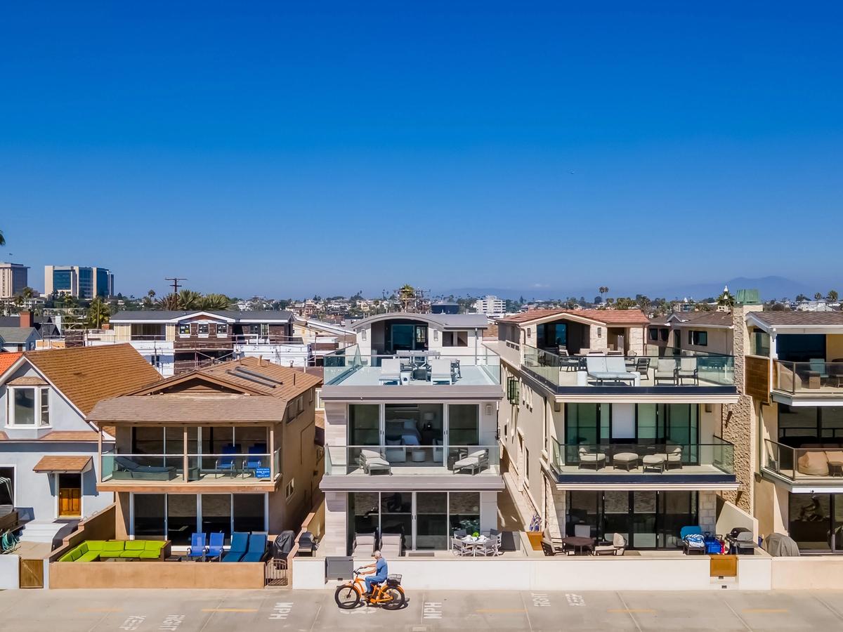 Modern beachfront homes along the Newport Beach boardwalk, featuring luxury vacation rentals with glass balconies, ocean views, and direct beach access in Southern California.