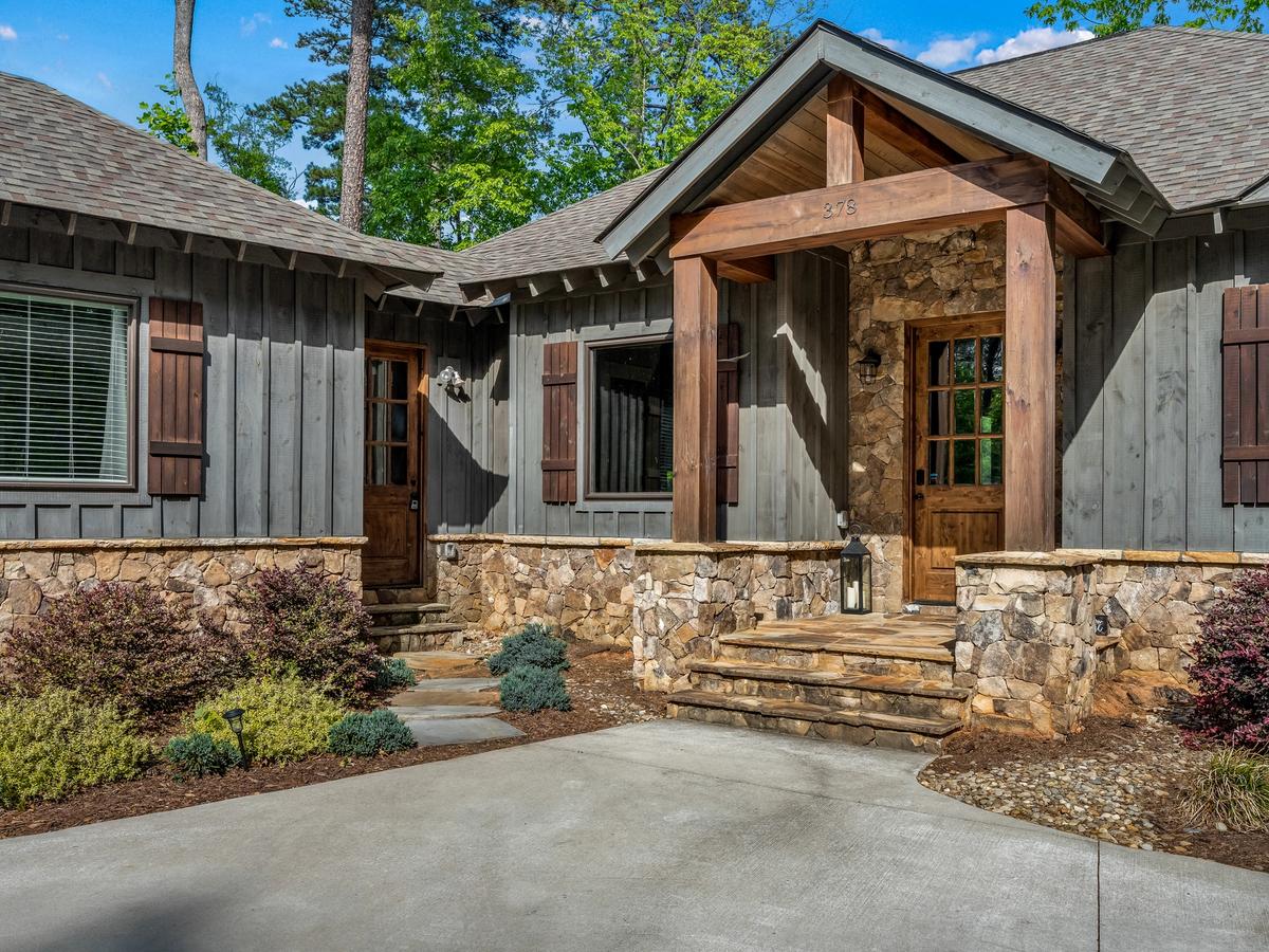 Rustic craftsman-style home with wood and stone exterior, wooden shutters, and a welcoming covered entryway.