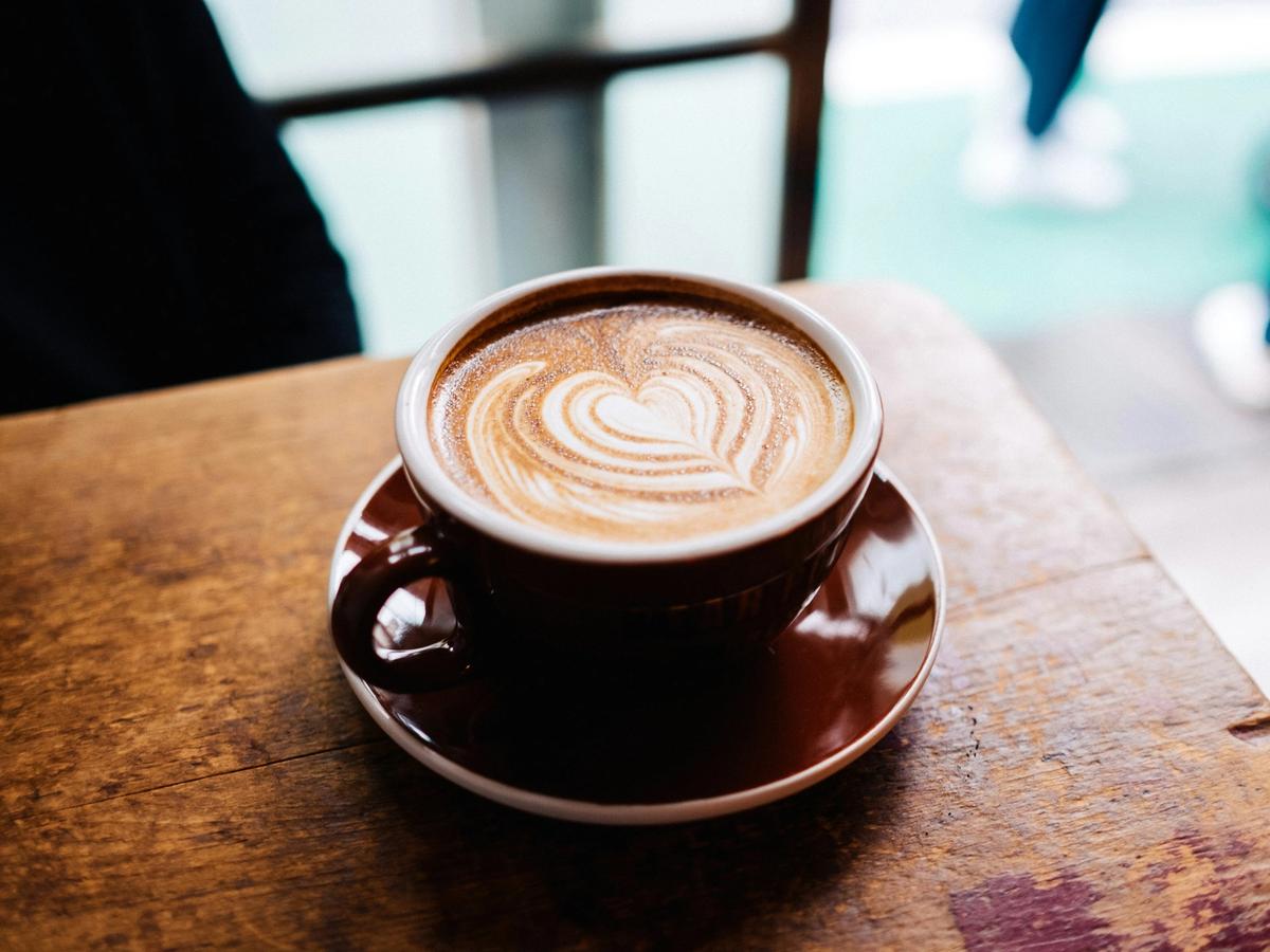 Coffee cup in brown coffee mug on plate and wooden table at shop